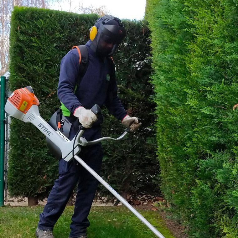 Empleado de Paisajismo La Rioja trabajando con una cortadora de hilo.